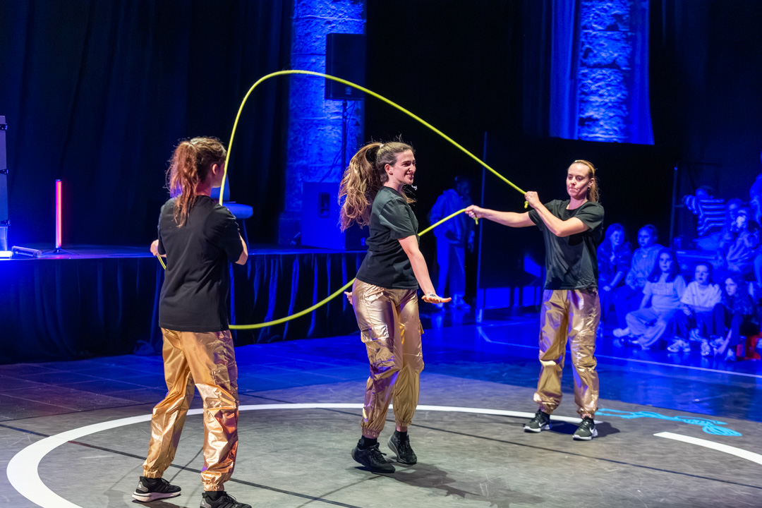 Crew in gold pants jumping under blue light